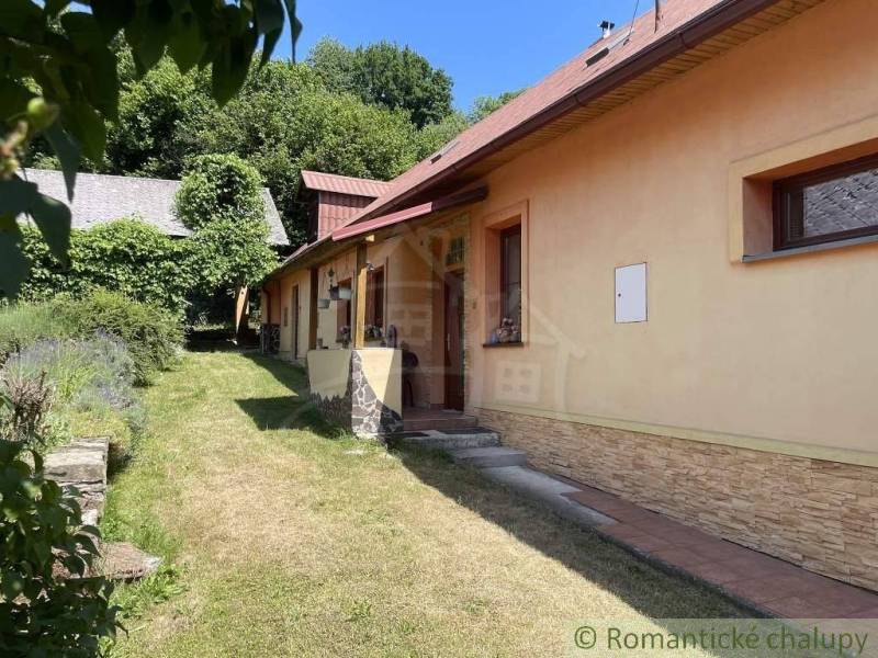 A family house in Medzev with a lawn, surrounded by trees and a hedge.