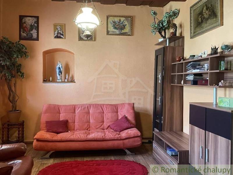 A living room in a family house with an orange wall, a red sofa, and wooden furniture.