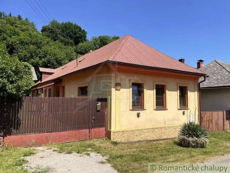 A family house in Medzev with a brown roof and a wooden fence on Green Street.