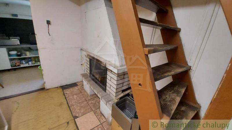 Wooden stairs next to the fireplace in the cottage kitchen.