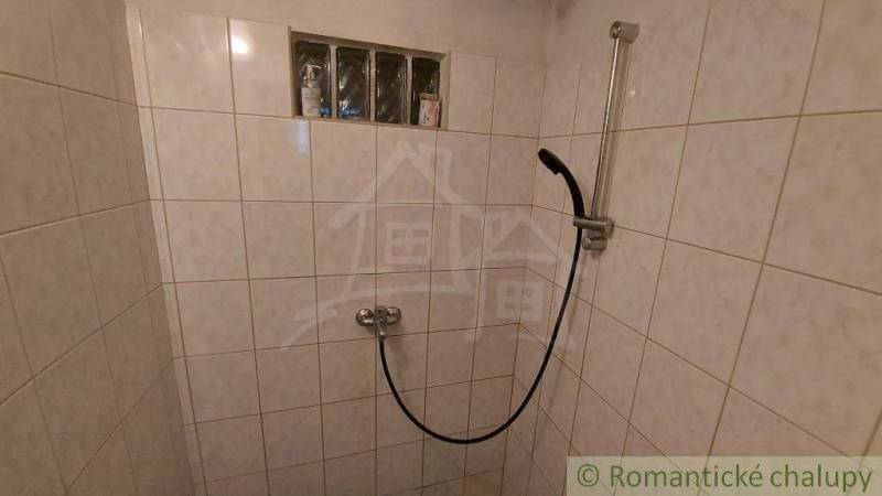 A shower corner in a cabin with tiles and a showerhead.