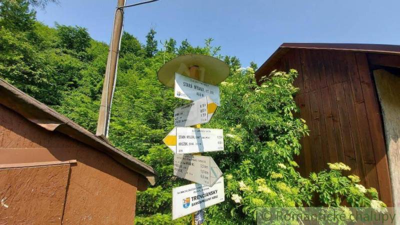 A signpost near the cottage by Myjava, surrounded by greenery and wooden structures.