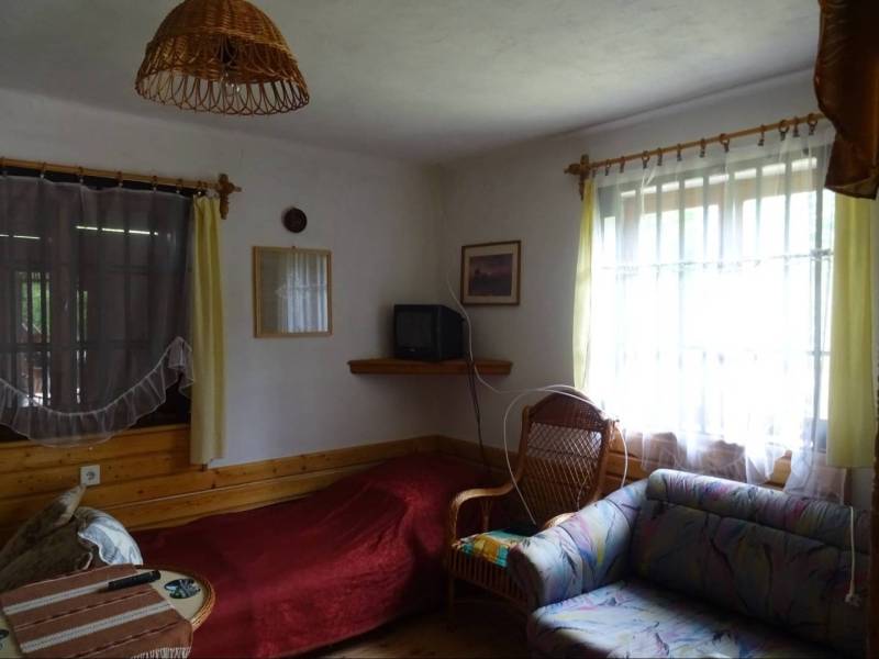 Living room with a sofa, television, armchair, and curtains in a family house.