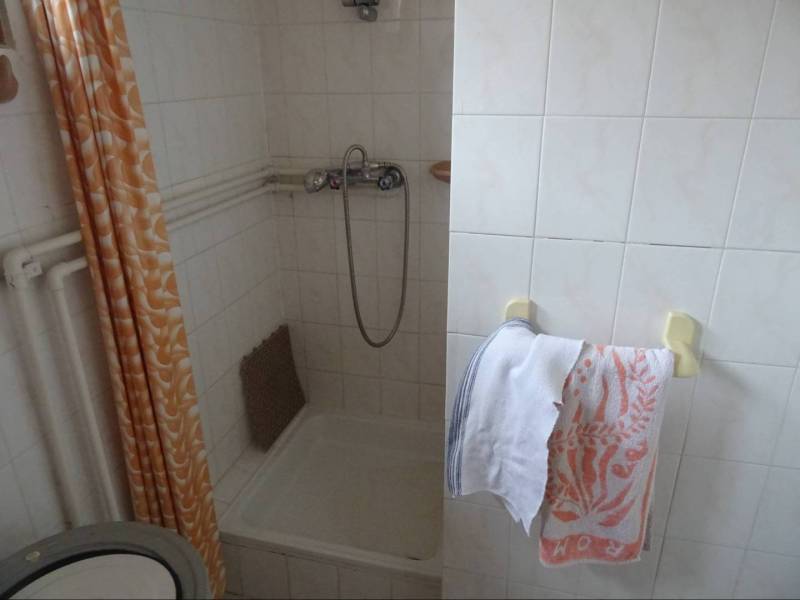 A bathroom in a family house with tiles, a shower, and towels on a rack.