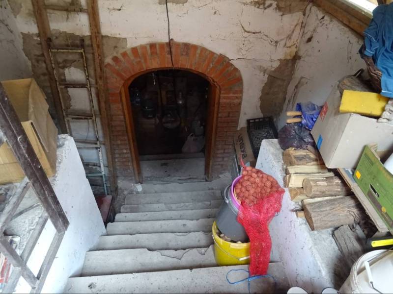 A staircase in the basement of a family house with supplies of wood and cardboard boxes.