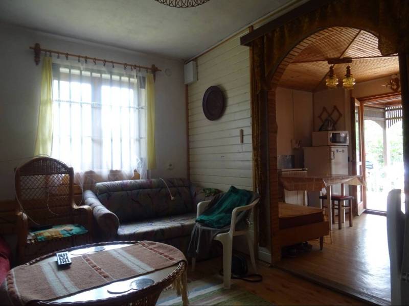Living room in a family house with rattan chairs, a sofa, and a view of the kitchen.