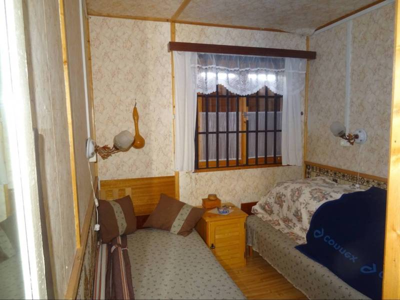 Bedroom in a family house with beds and patterned wallpaper.
