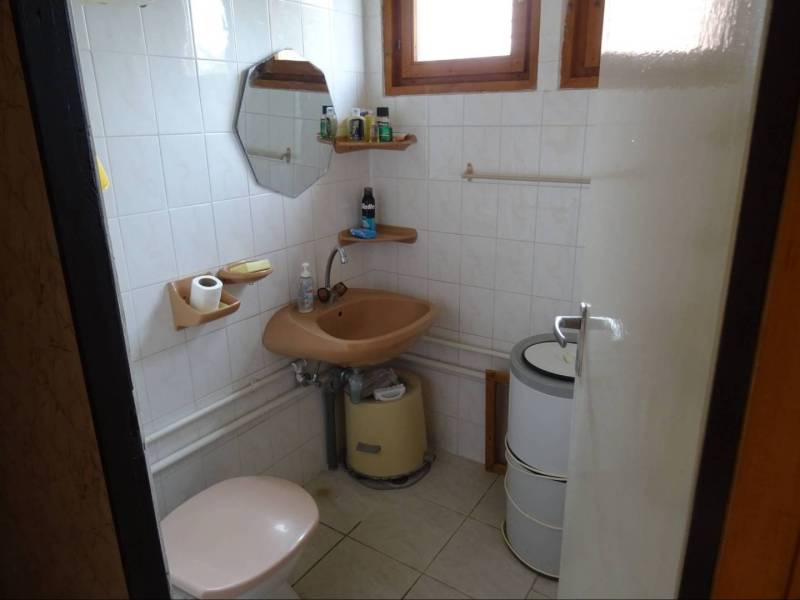 Bathroom in a family house with a simple sink, toilet, and mirror.