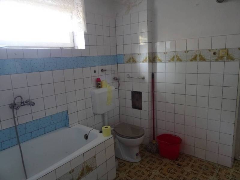 Bathroom with a bathtub, toilet, and rectangular tiles in a family house.