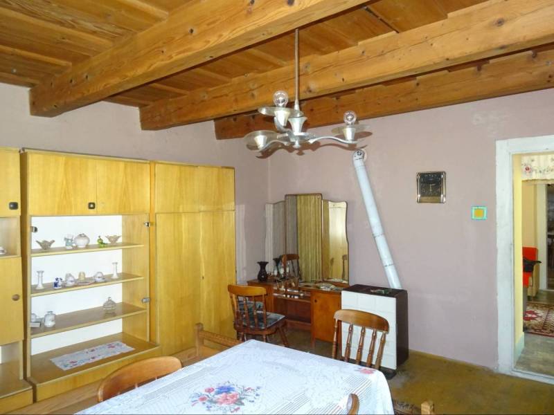 The dining room of a family house with a wooden ceiling, furniture, and tiles.