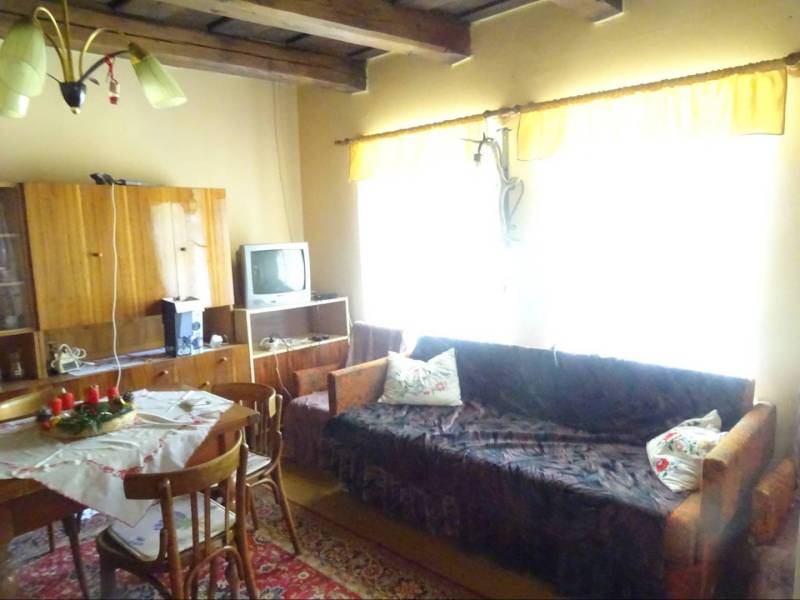 A living room in a family house furnished with wooden furniture, a television, and a dining table.