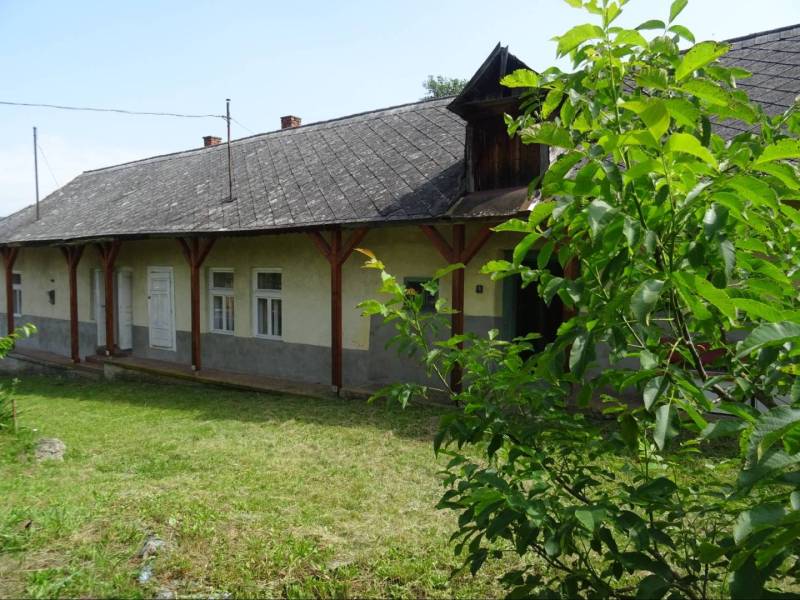 An older family house in Tornaszentandrás with a grassy garden and a covered veranda.