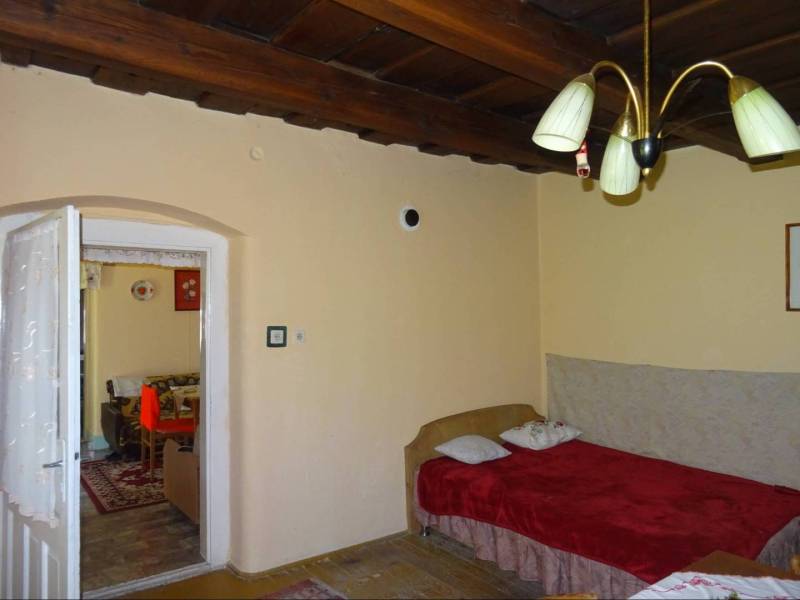 A room in a family house with a wooden ceiling, a sofa, and a chandelier in Mediterranean style.