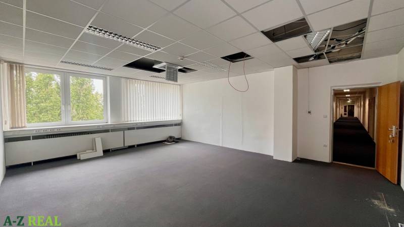 Empty office space with an open ceiling and a large window.