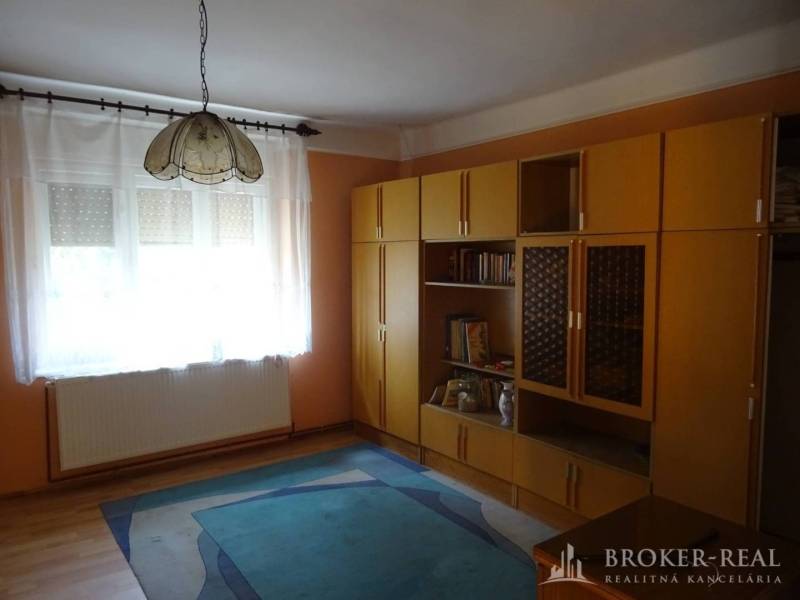 A room in a family house with modular furniture, a carpet, and pendant lighting.