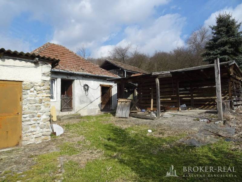 The courtyard of an older family house in Füzérkomlós with a wooden shelter and a brick wall.