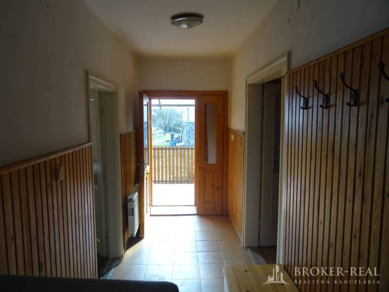 Entrance hall in a family house with wooden paneling and open doors to the porch.