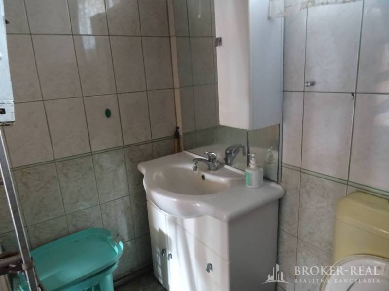 A sink and a washing machine in the bathroom of a family house, tiles with green details.