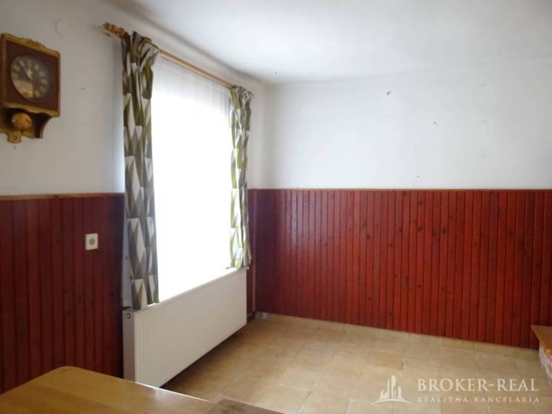 Room in a family house with wooden paneling, curtains, and a wall clock.