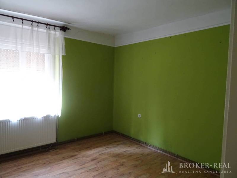A room in a family house with a wooden floor and green walls.