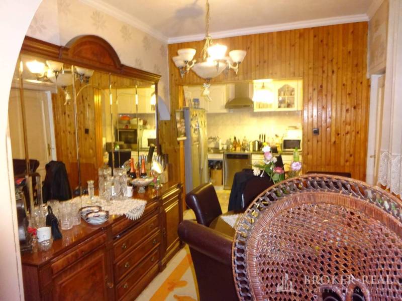 A dining room in a family house with wooden furniture and mirrors, overlooking the kitchen.