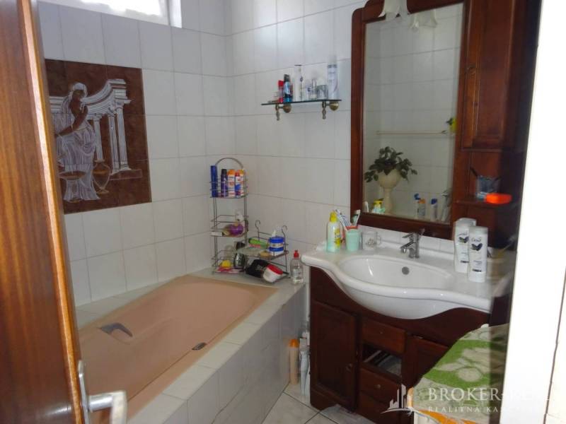 A bathroom in a family house with a bathtub, mirror, and wooden sink.