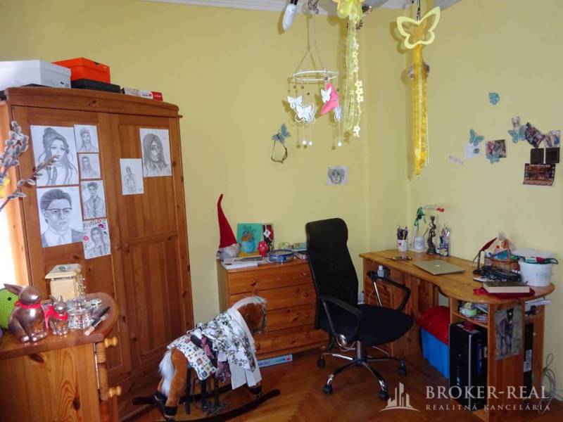 A room in a family house with a desk, chair, and a bulletin board decorated with pictures.