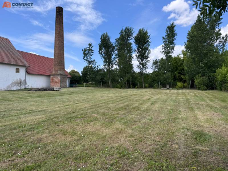 A chimney and a building on a grassy plot in Zemianske Sady on Zemianske Sady Street, warehouses and halls.