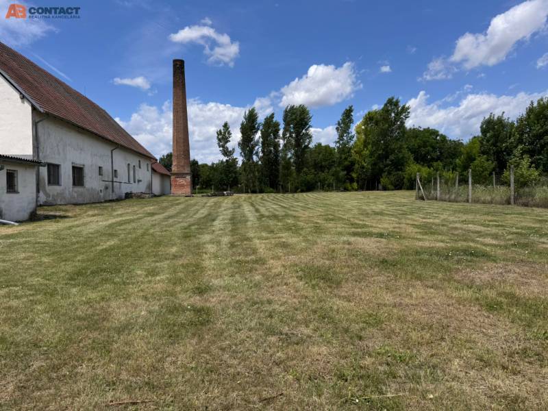 A grassy plot with a chimney and a building in Zemianske Sady near Zemianske Sady Street, warehouses and halls.