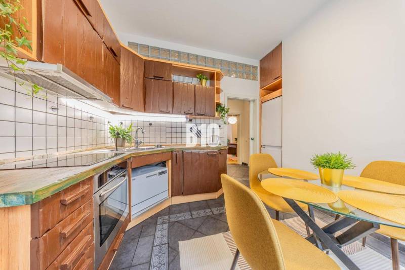Kitchen corner with wooden cabinets and a dining table in a 2-room apartment.