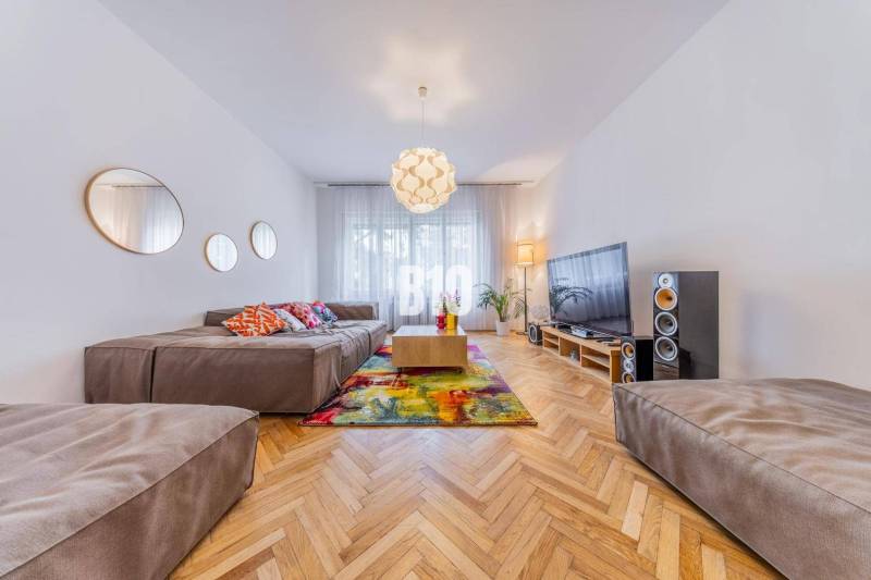 Living room in a two-room apartment with a comfortable sofa, television, and colorful cushions.