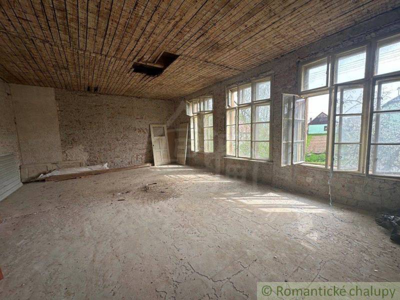 A spacious room with large windows and a wooden ceiling in a family house.
