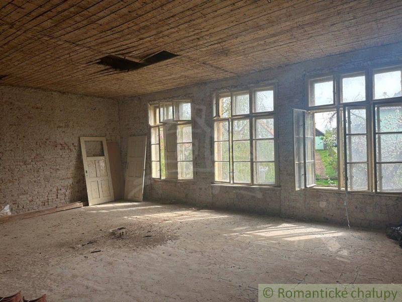 An empty room in a family house with large windows and leaning doors.