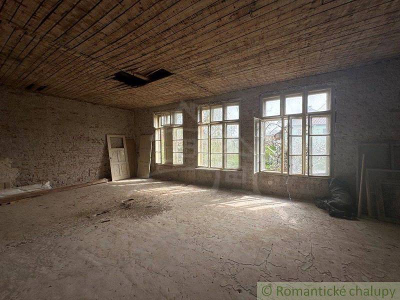 A spacious room with large windows and unfinished walls in a family house.