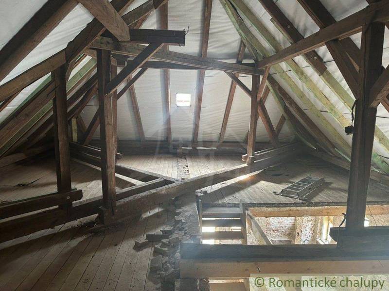 Attic in a family house with wooden beams and a hole in the floor.