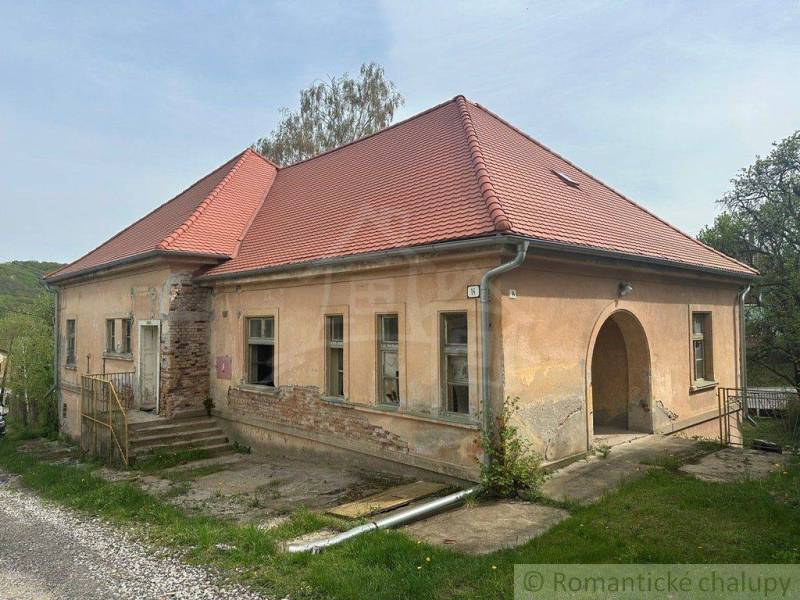 An older family house in Rimavská Sobota, with peeling plaster, a red roof, in a rural setting.