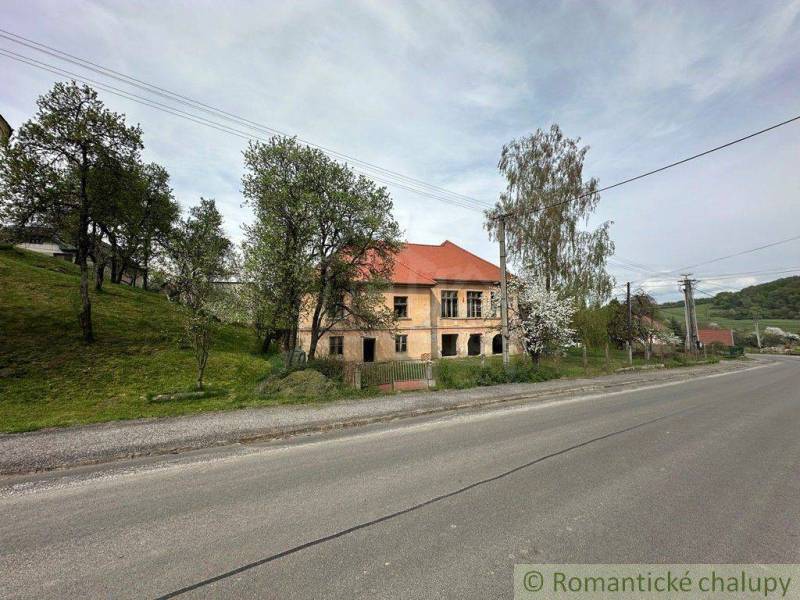 A family house in Rimavská Sobota by the road, surrounded by trees and grass.