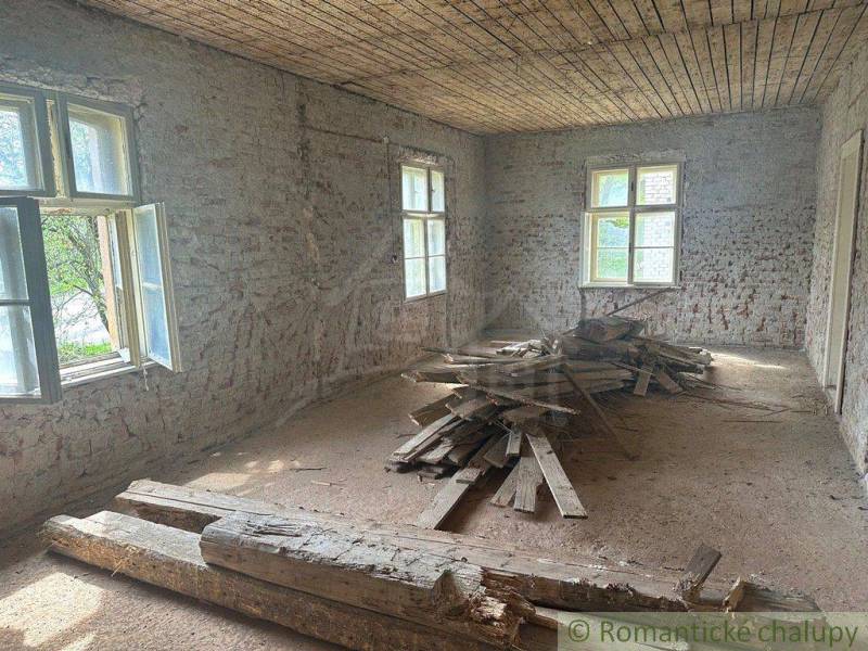 An older room of a family house with an exposed brick wall and wooden planks on the floor.