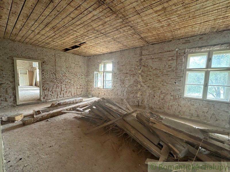 A shabby room with exposed bricks and a pile of wood in a family house.