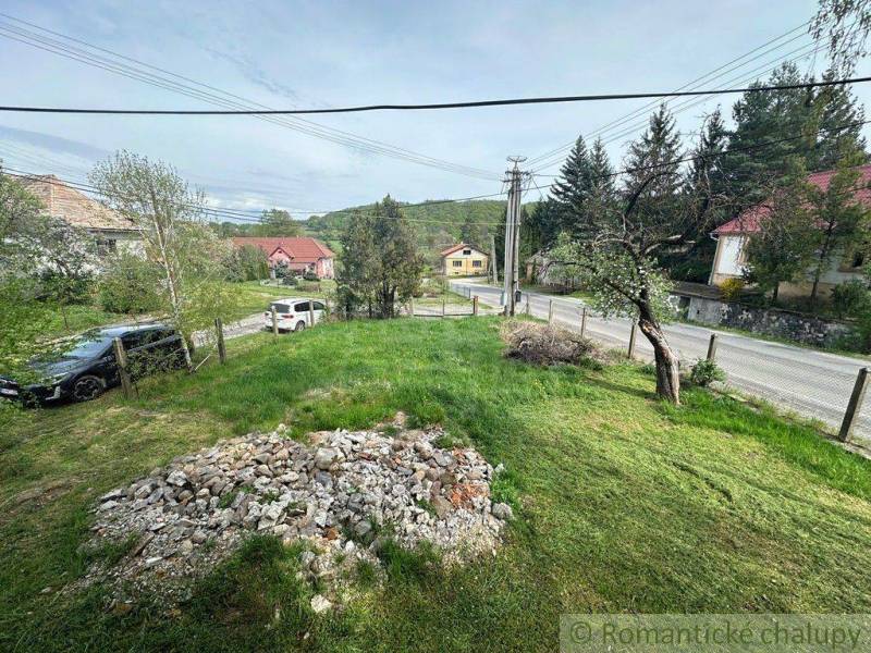 A garden of a family house in Rimavská Sobota with a lawn and gravel near the road.
