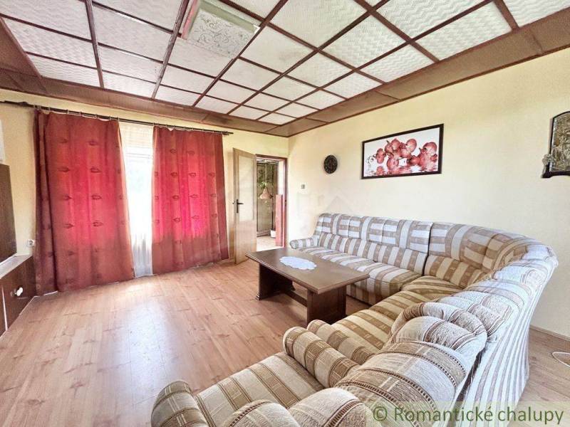 Living room with a striped sofa, wooden floor, and burgundy curtains in a family house.