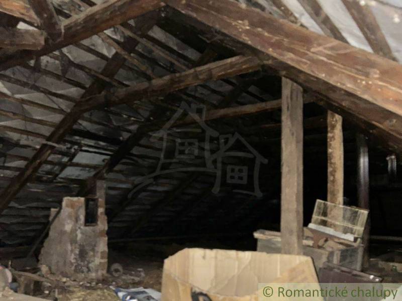 Attic in a family house with wooden beams and a chimney.