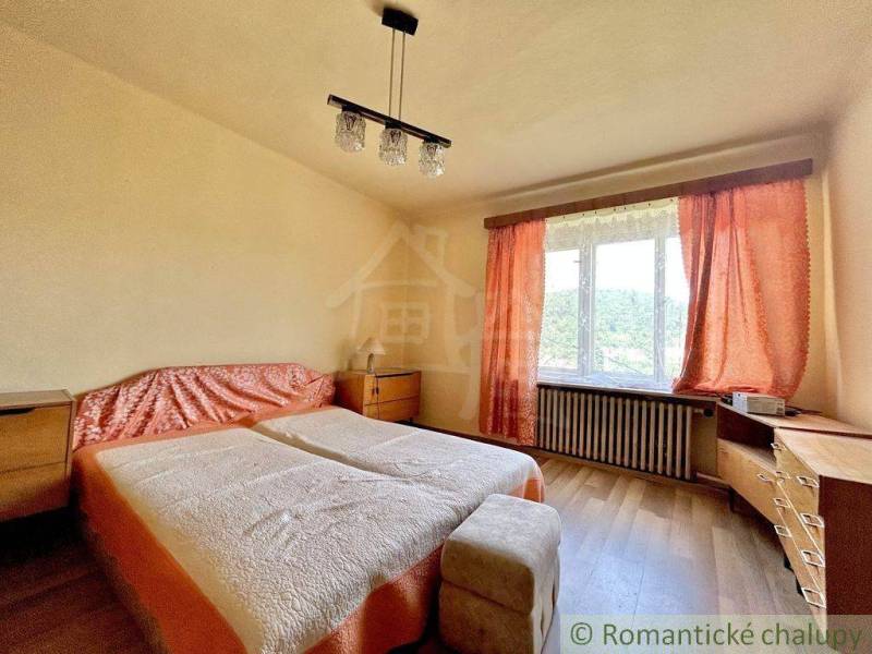 A bedroom with two beds and orange curtains in a family house.