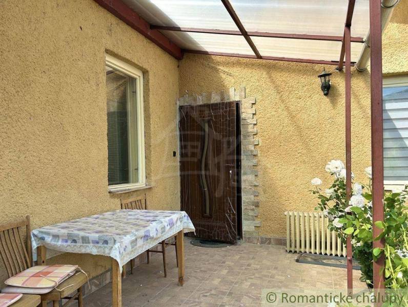 A family house in Gemerská Hôrka with a terrace, table, chairs, and blooming roses.