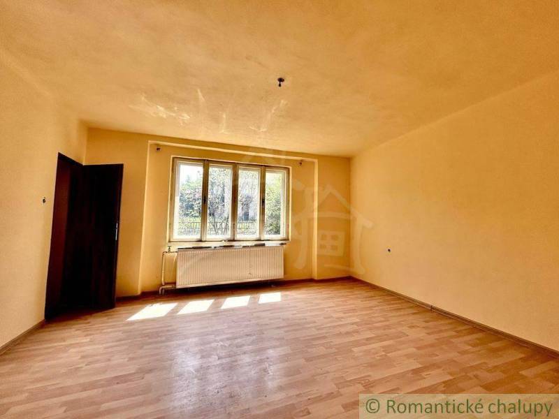 A bright room with laminate flooring and a large window in a family house.