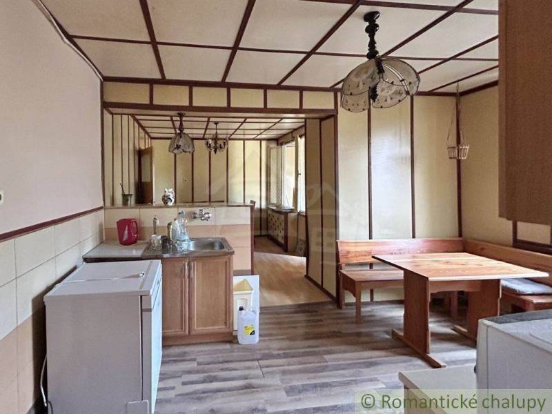 A kitchen in a family house with a stove, wooden seating, and indoor lamps.