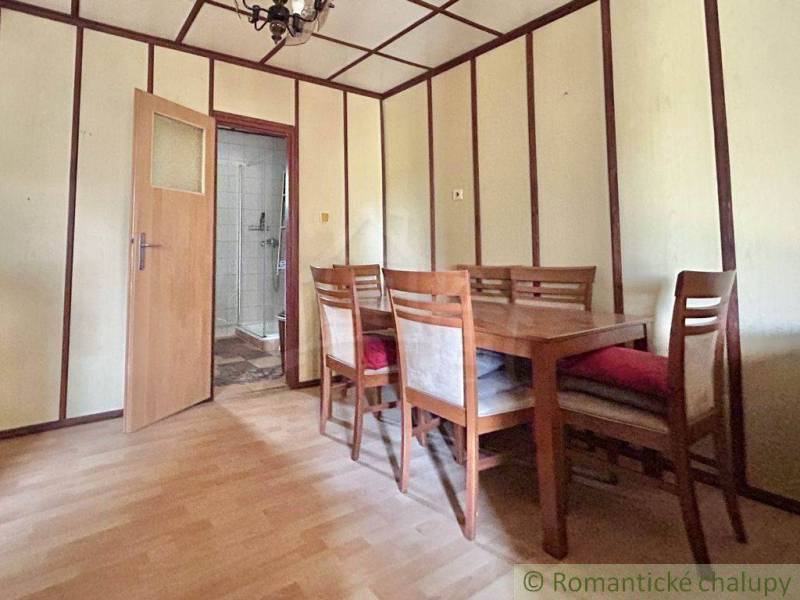 A dining room with wooden furniture and open doors in a family house.