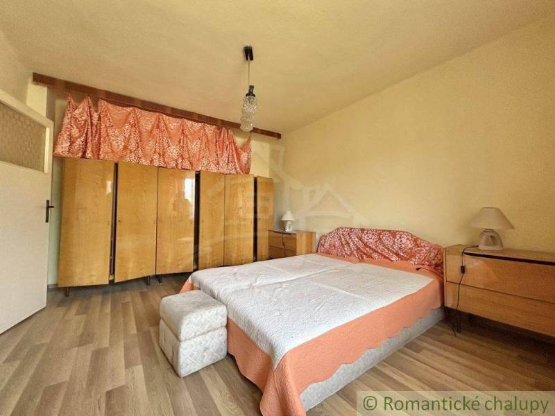 A bedroom in a family house with a large bed, wardrobes, and wooden furniture.