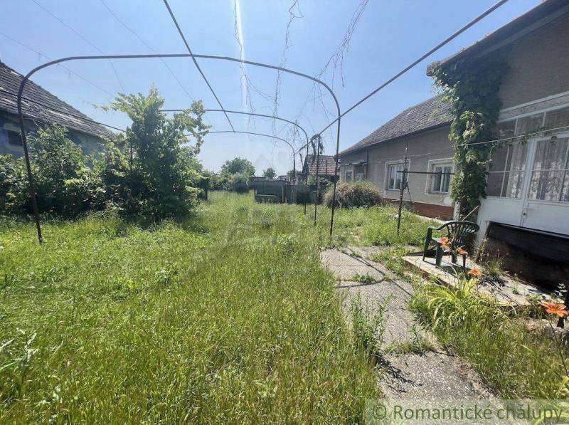 A family house in Nové Zámky surrounded by unkempt grass and garden furniture.