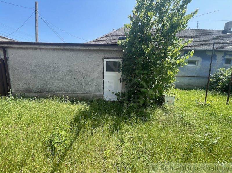 A family house in Nové Zámky with greenery and a white building on the property.